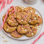 White chip peppermint cookies on a white plate with candy canes on the table.