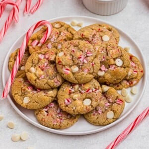 White chip peppermint cookies on a white plate with candy canes on the table.