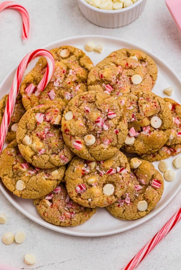 White chip peppermint cookies on a white plate with candy canes on the table.