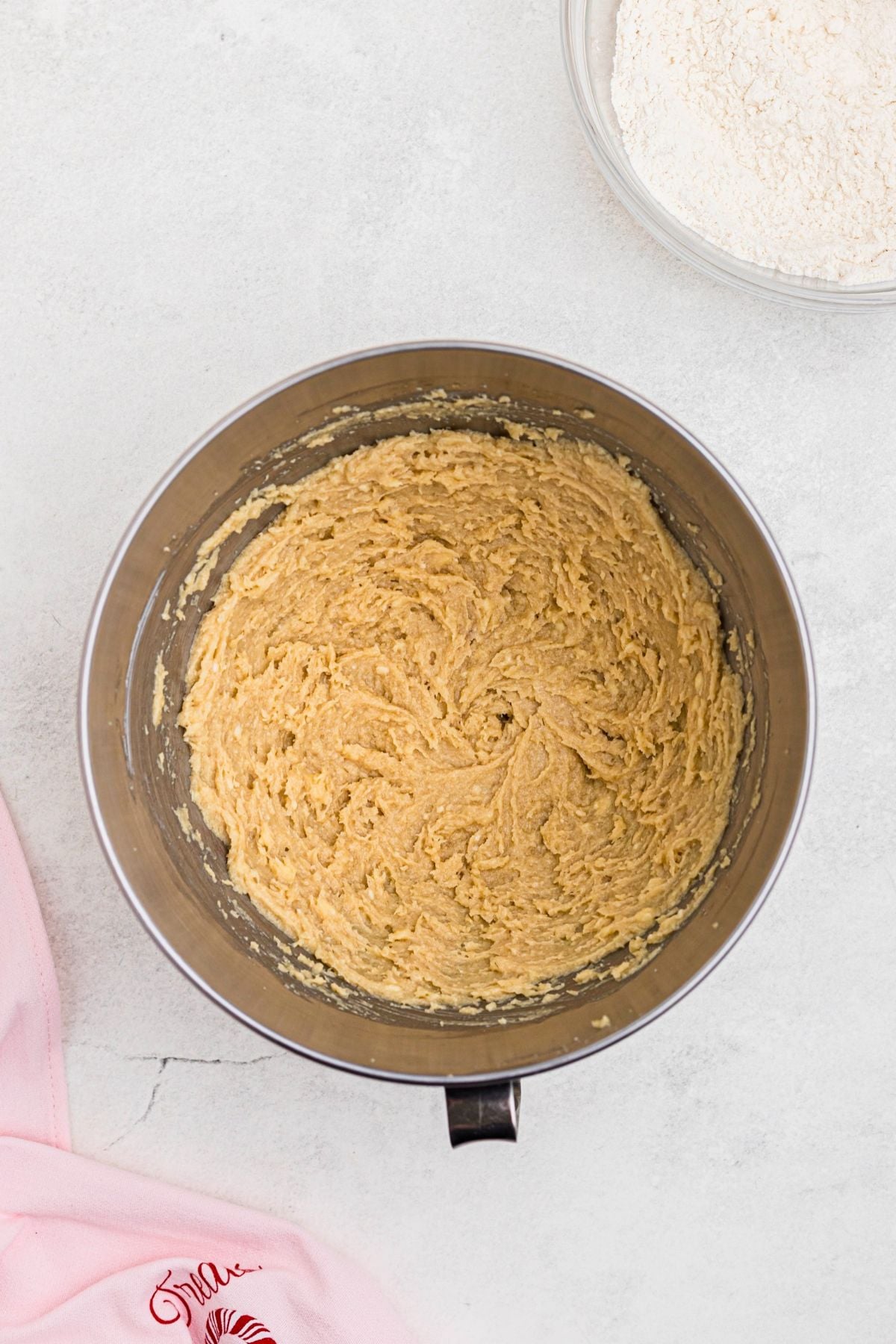Butter, sugars, and extracts mixed together in a mixing bowl on a marble table. 