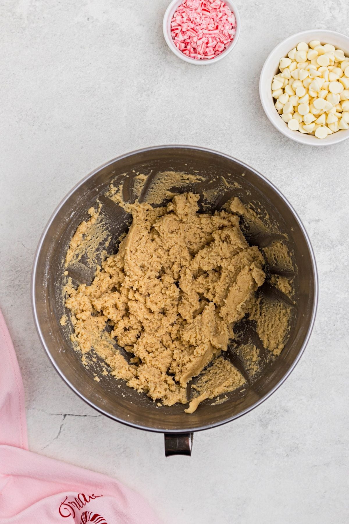 Cookie dough in a mixing bowl, on a white marble table. 