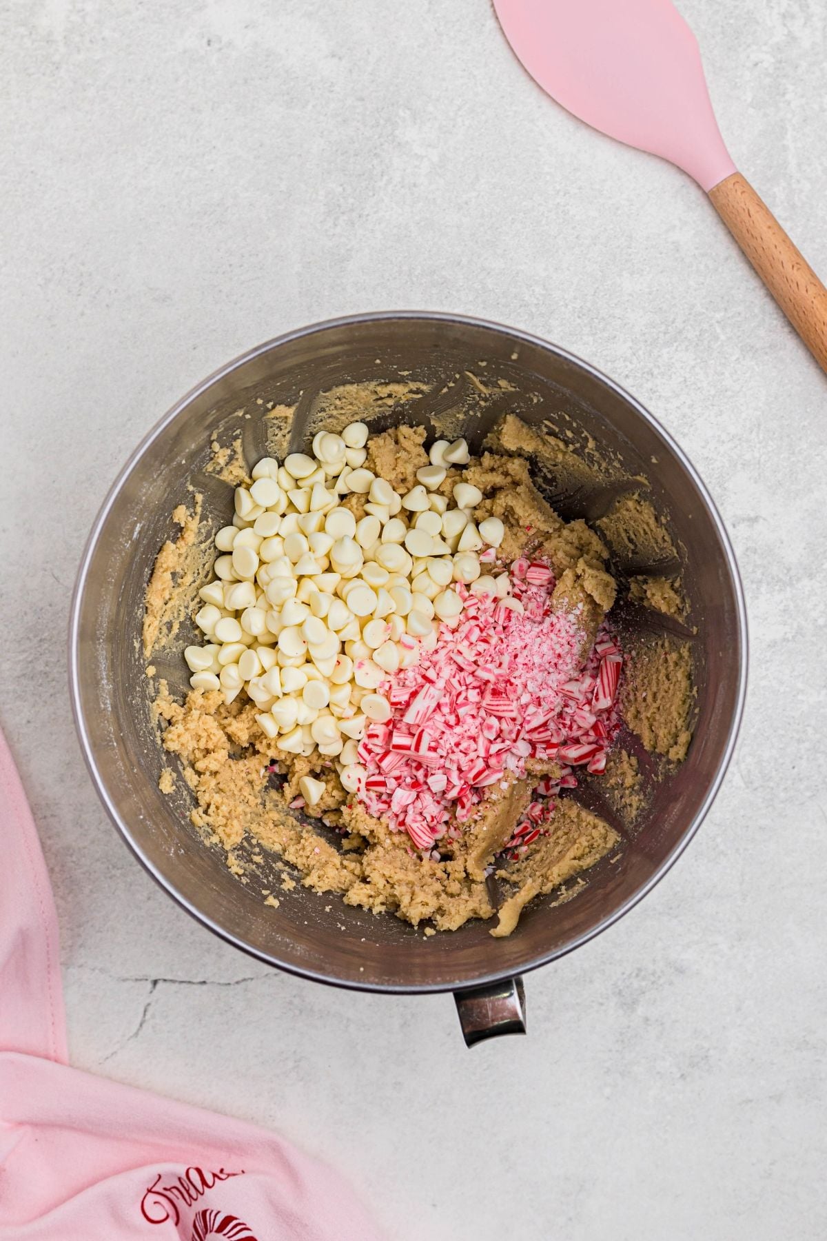 Candy cane, white chips, and cookie dough, in mixing bowl. 