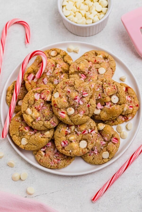 White chip peppermint cookies on a white plate with candy canes on the table.
