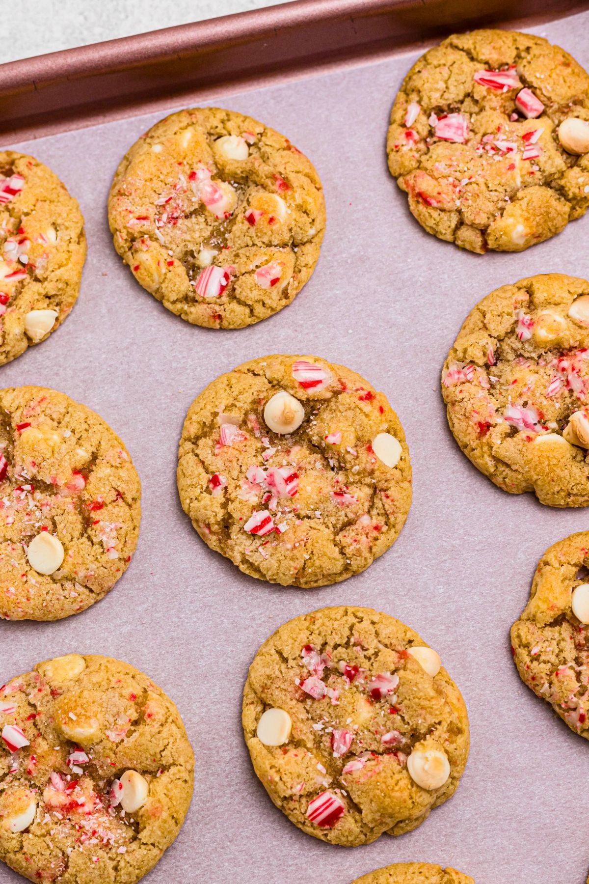 Golden baked cookies on a pink baking sheet lined with parchment paper. 