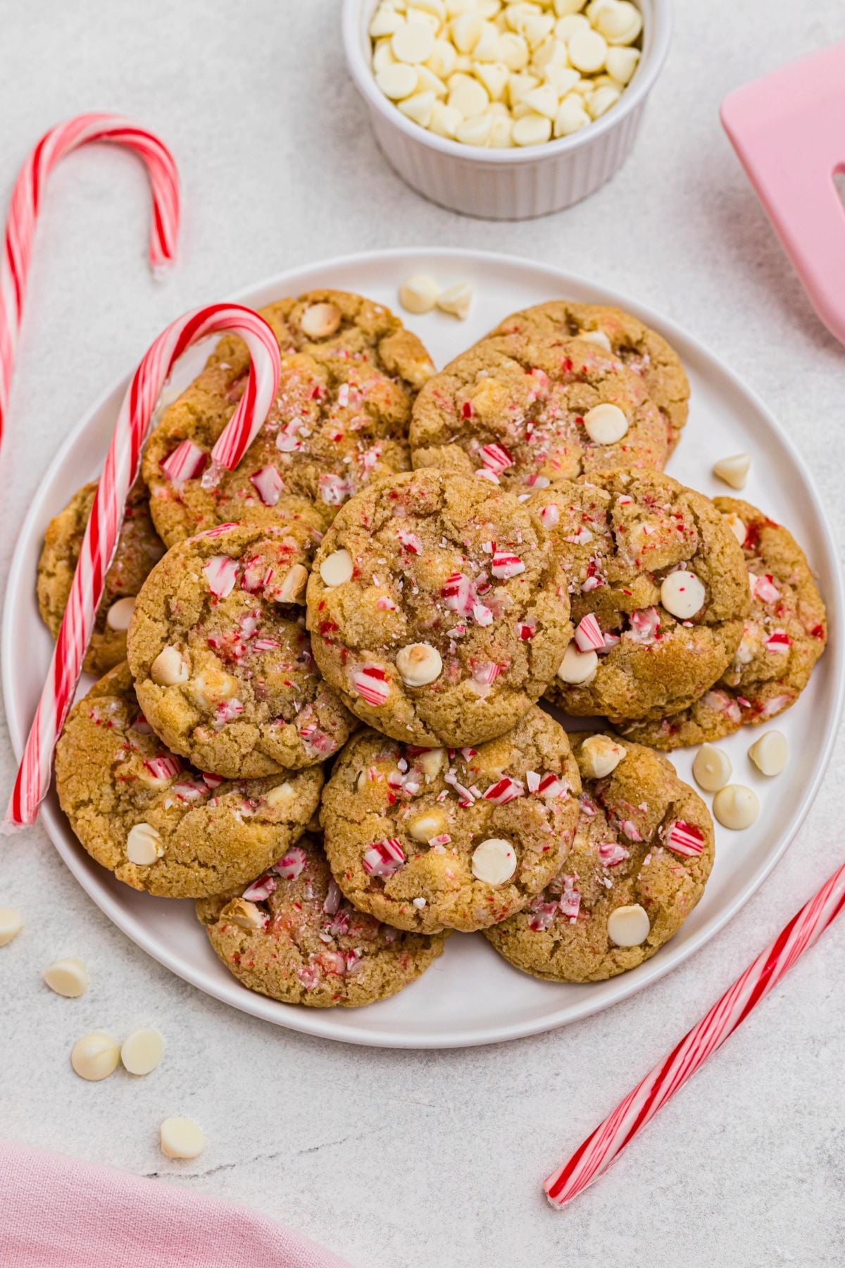 White chip peppermint cookies on a white plate with candy canes on the table. 